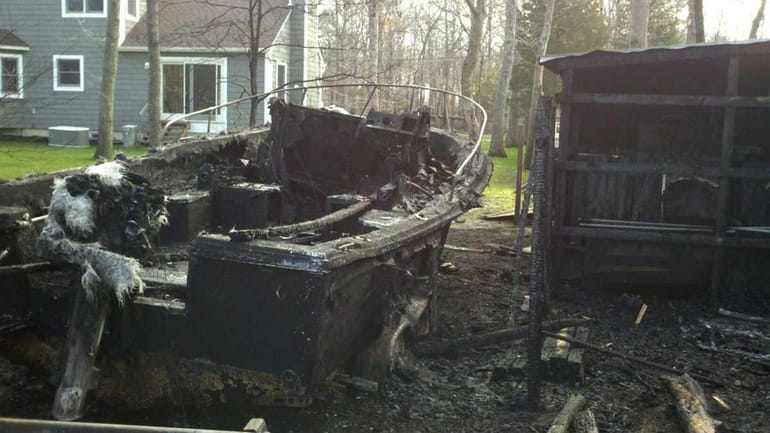 A burned up boat sits behind a house on Wading...