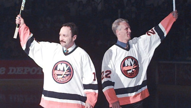 Islanders greats Brian Trottier and Mike Bossy wave to the...