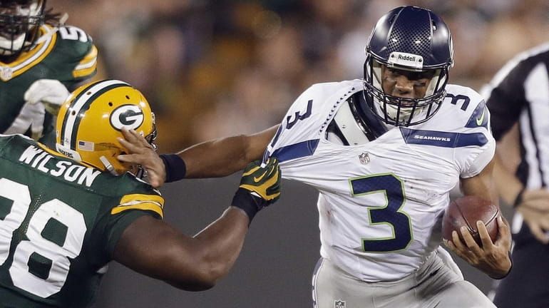 Seattle Seahawks quarterback Russell Wilson tries to get away from...