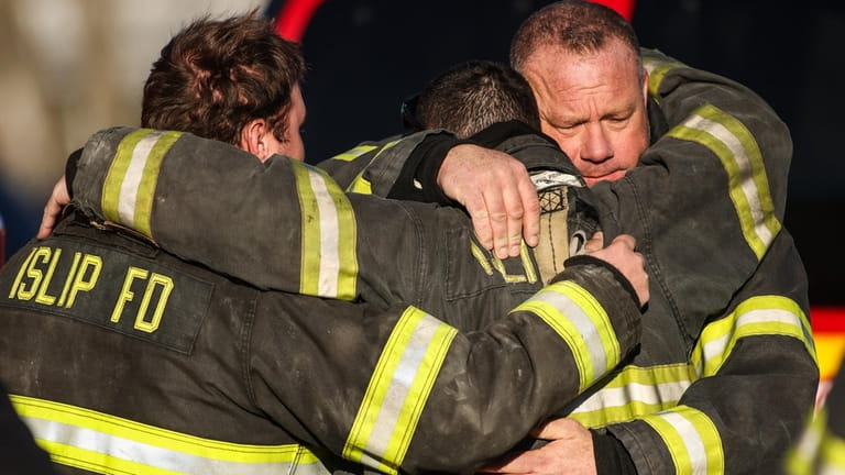 Firefighters from the Islip Fire Department embrace after Moon's body arrived...