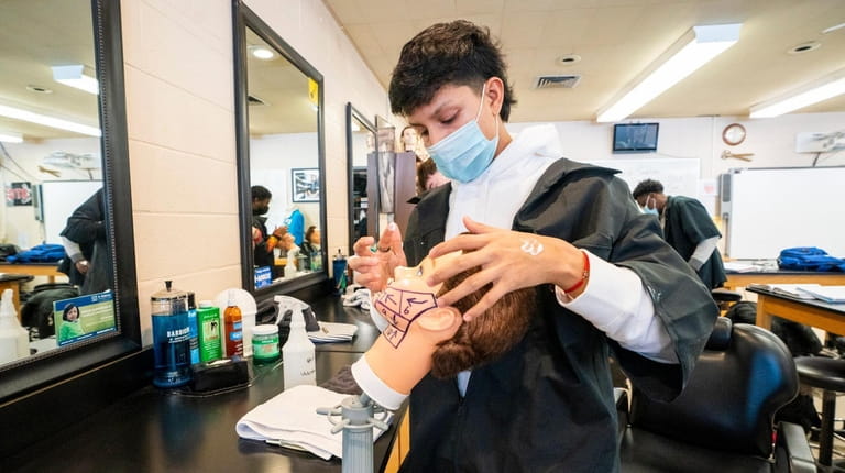 Anthony Supliguicha, 18, of Bellport High School, shaves a mannequin in barbering...
