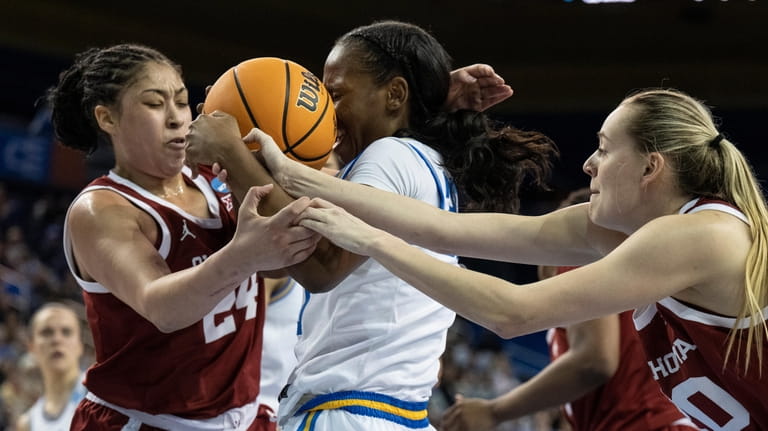 UCLA guard Charisma Osborne, center, battles for the ball against...
