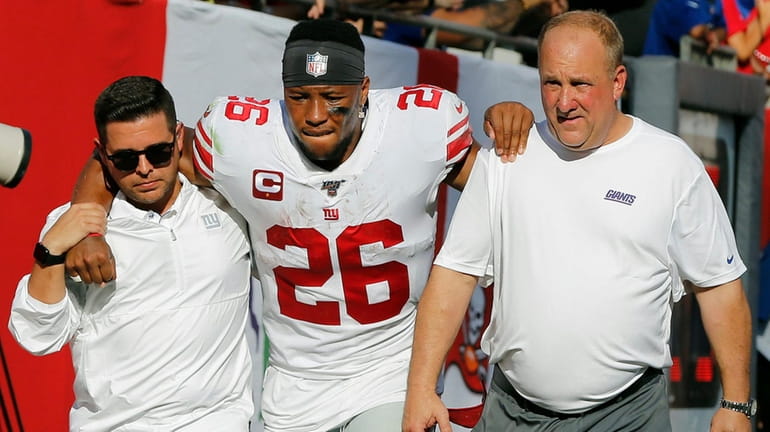 Giants running back Saquon Barkley gets helped off the field...
