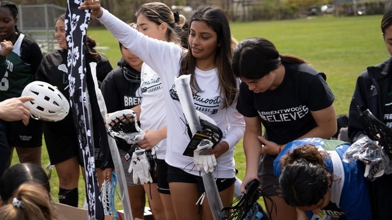 Brentwood girls lacrosse players receiving a lacrosse equipment donation from...