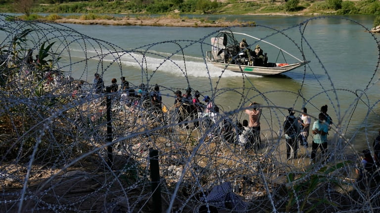 Migrants who crossed into the U.S. from Mexico are met...