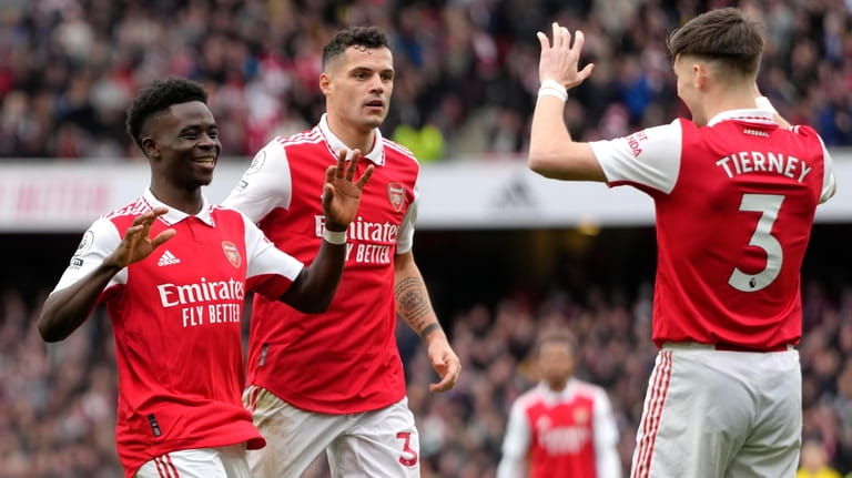 Arsenal's Bukayo Saka, left, celebrates with teammates after scoring his...