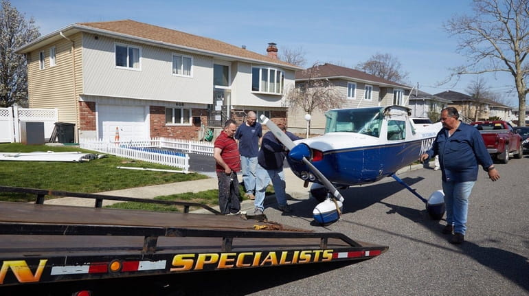 Workers remove a plane from the home of Harold Guretzky...