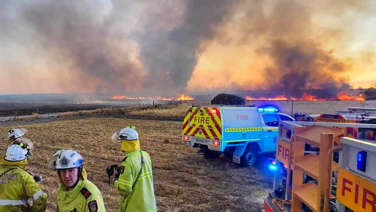 West Australian firefighters watch as grassland burns near the West...