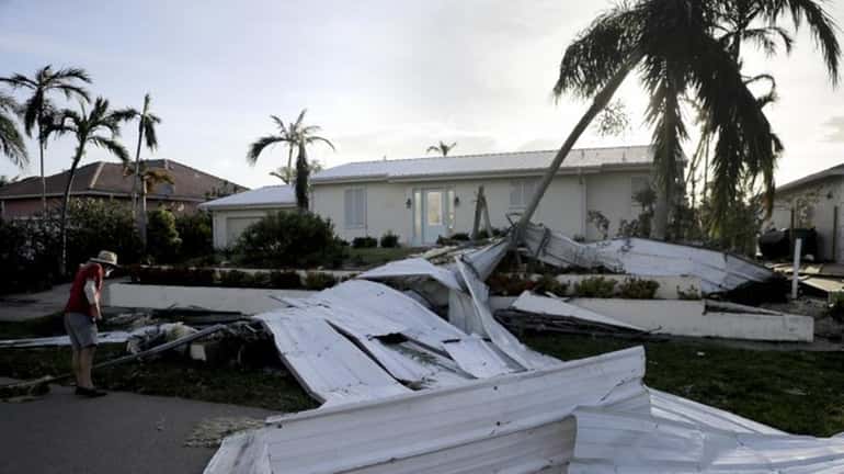 A roof is strewn across a home's lawn as Rick...