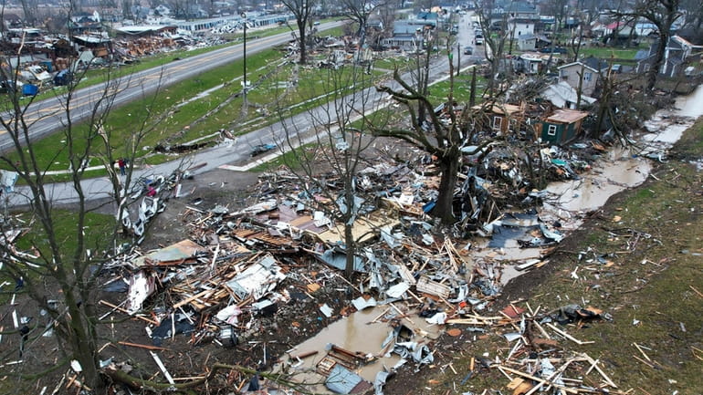 Debris scatters the ground near damaged homes following a severe...