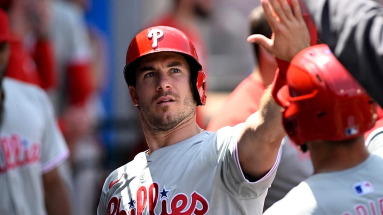 Philadelphia Phillies' J.T. Realmuto greets teammates after scoring with Whit...