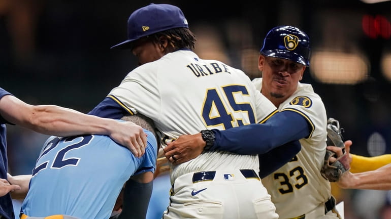 Milwaukee Brewers' Abner Uribe (45) is held back by Quintin...