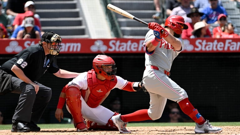 Philadelphia Phillies designated hitter Kyle Schwarber, right, hits a two-RBI...